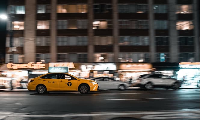 Yellow taxi on a city road at night